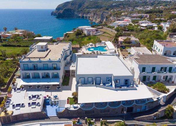 Vista aerea di un hotel costiero con piscina, mare blu e scogliere.